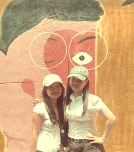 Two friends in front of a pink face mural in Kuala Lumpur, shot on Kachak.
