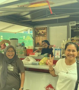 Two women laughing behind a nasi lemak stall, shot on Kachak.